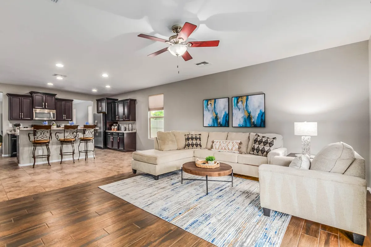 A cozy great room is featured, complete with a large sectional sofa, a coffee table, wall art, and direct sightlines into the kitchen area. The atmosphere is both welcoming and comfortable, perfectly suited for group movie nights or festive gatherings.